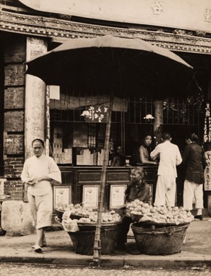 Lot 73 - Hoppé (Emil Otto, 1878-1972). A woman selling oranges outside a money changer's shop, c. 1930s